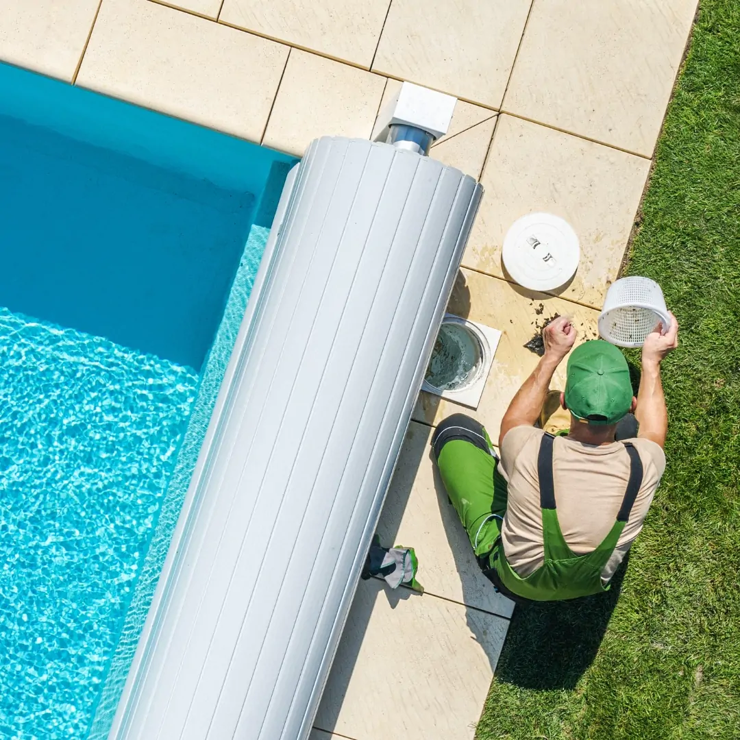 Technician servicing an inground pool cover and reel during a seasonal pool closing